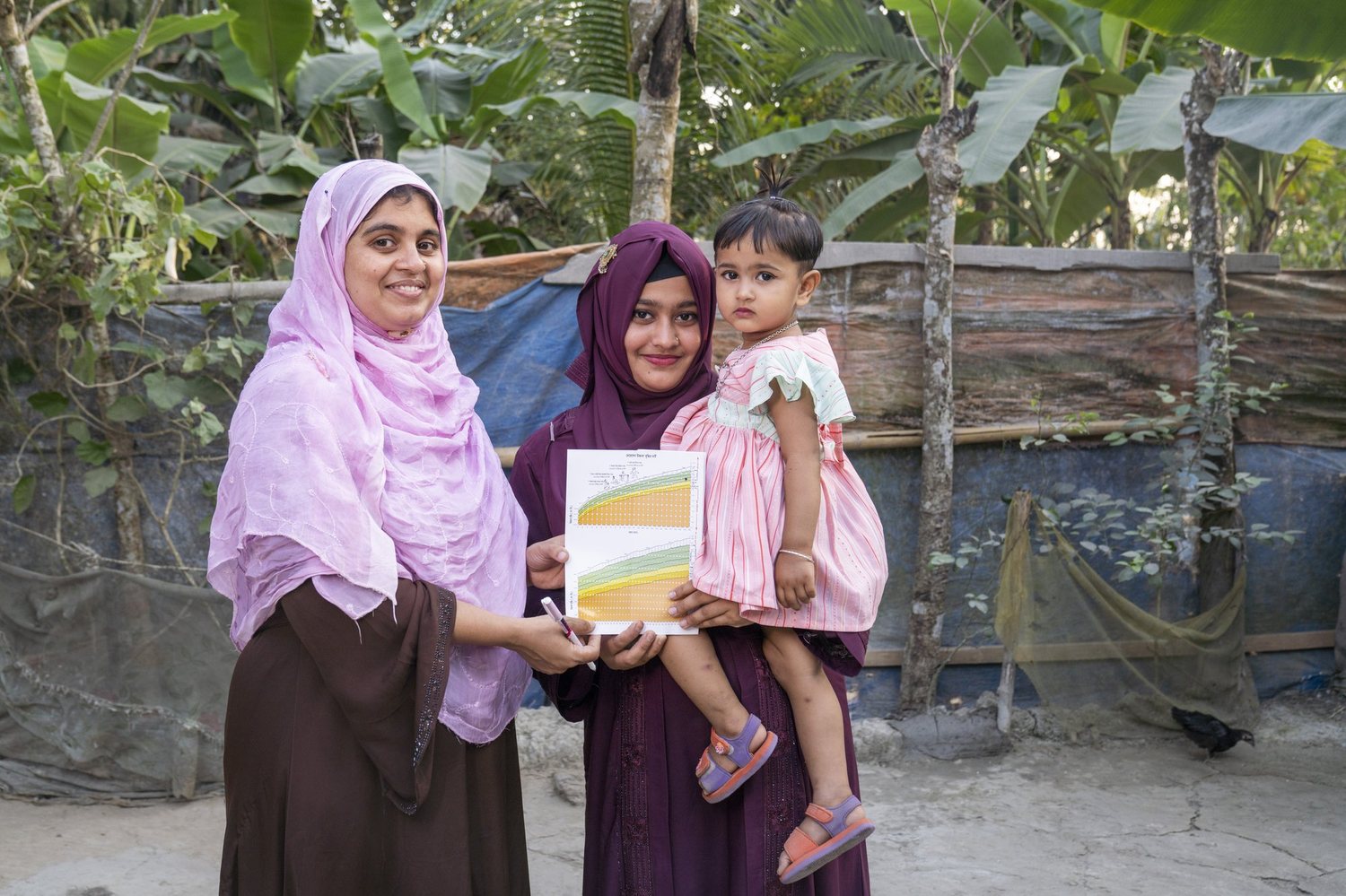 A community health worker reviews a child's growth chart with a mother in Bangladesh