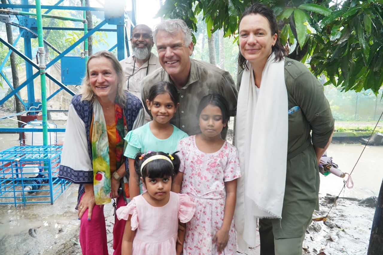 Joke Le Poole, Ambassador Joris van Bommel, Inge Klaassen and Yameen Farook standing beside a Max TapWater tower with children from the community in Bakerganj, Barishal