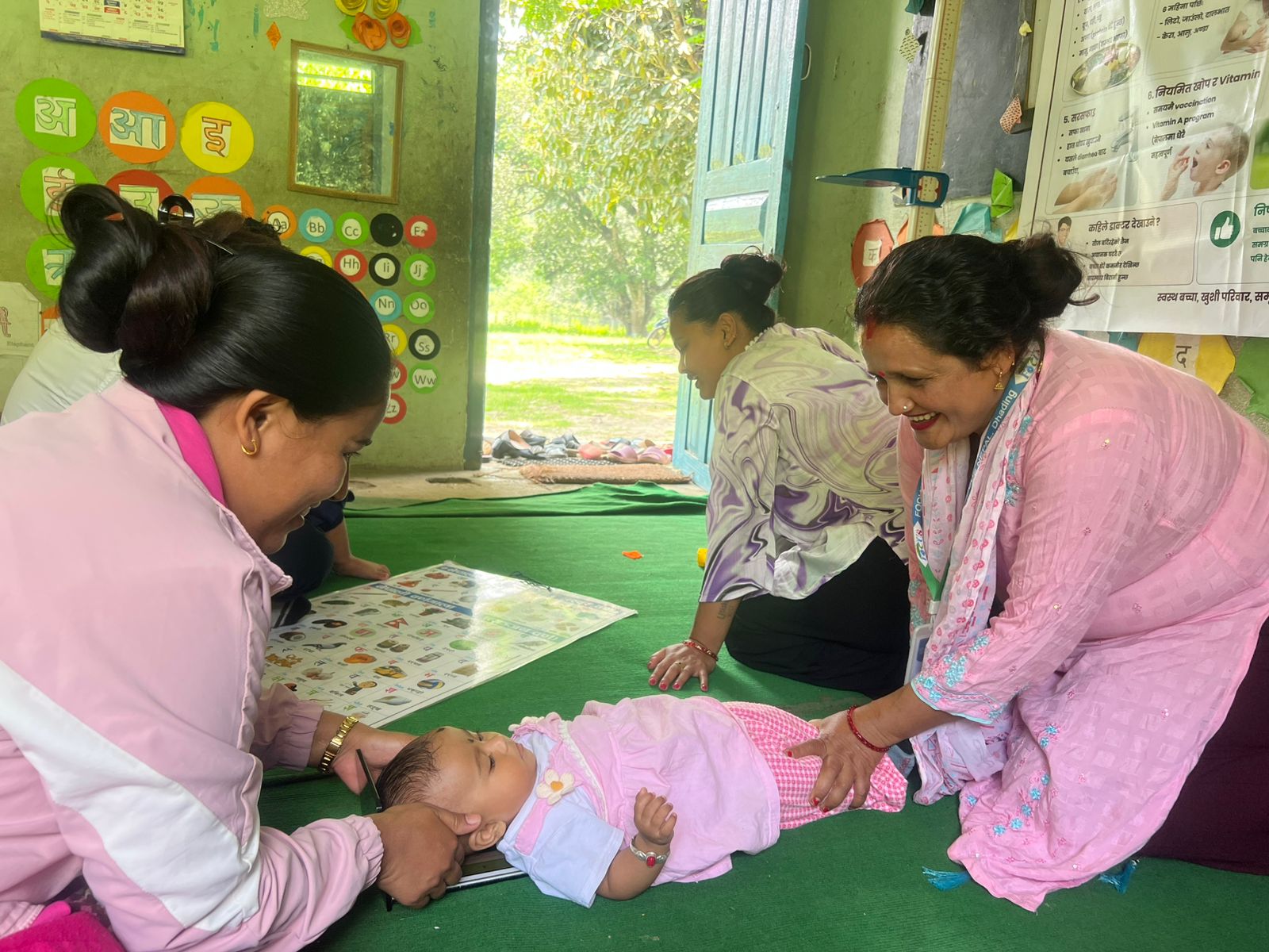 A community mobiliser and a Female Community Health Volunteer measure the length of an infant during Nepal's National Nutrition Assessment Campaign